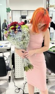 Our daughter, holding a beautiful bouquet of flowers, after receiving her cosmetology certification.