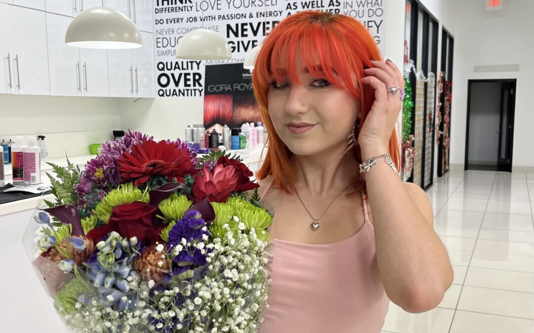 My daughter holding a bouquet of flowers before her beauty school certification ceremony.
