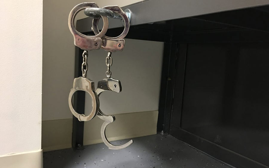 Partially opened handcuffs within prison walls.